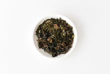 White bowl filled with organic oolong tea leaves on a white background