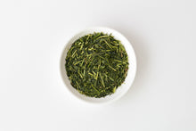 White bowl filled with Shiraore green tea leaves on a white background